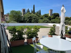 un patio con una mesa blanca, sillas y plantas en Barchi Resort - Apartments & Suites, en San Felice del Benaco