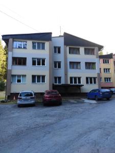 un bâtiment avec trois voitures garées devant lui dans l'établissement Apartmán Anna, à Demänovská Dolina