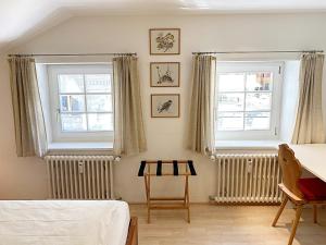 1 dormitorio con 2 ventanas, 1 cama y 1 mesa en Dachwohnung im Alpenstil, 60m2 für 2P, mit Garage - BM186 en Pontresina