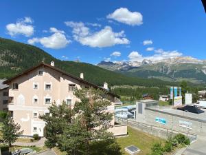 - une vue sur un bâtiment avec des montagnes en arrière-plan dans l'établissement Dachwohnung im Alpenstil, 60m2 für 2P, mit Garage - BM186, à Pontresina