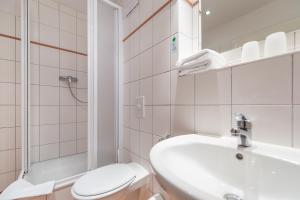 a bathroom with a sink and a toilet and a shower at Hotel Mukran in Sassnitz