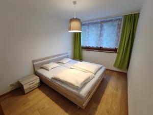 - une chambre avec un lit et une fenêtre avec des rideaux verts dans l'établissement Apartmán Anna, à Demänovská Dolina