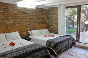 two beds in a room with a brick wall at Jabula Lodge in Marloth Park