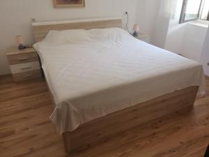 a bedroom with a bed with white sheets and wooden floors at VELI LOŠINJ Rovenska 52 in Veli Lošinj