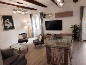 uma sala de estar com uma televisão e uma mesa e cadeiras em Beautiful Old Town flat, near the beach em Nice