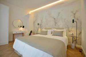 a white bedroom with a large bed and a mirror at Plaza Mina Suites - Adults Recommended by Luxury Suites Cadiz in Cádiz