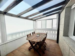a table and chairs on a balcony with a large window at Apartamentos Miramar Playa in Raxo