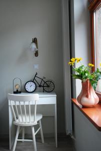 un escritorio blanco con una silla, un reloj y una planta en Apartament - Przy Rynku en Tarnowskie Góry