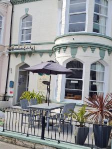a table and chairs with an umbrella in front of a building at Glascoed Guest House in Llandudno