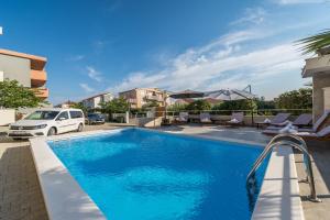 a swimming pool with a car parked next to a building at Apartments & Rooms Danivan Pool Villas in Novalja