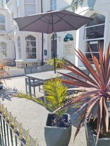 a patio with a table with an umbrella and plants at Glascoed Guest House in Llandudno