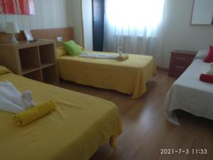 ラ・バニェサにあるHostal Caminitoのホテルルーム 黄色いシーツ付きのベッド2台付