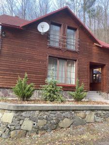 une maison en bois avec une horloge au-dessus dans l'établissement Домик в горах, à Turʼya Paseka