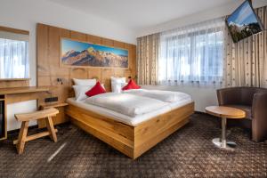 Habitación de hotel con cama grande y escritorio. en Alpenhotel Denninglehen, en Berchtesgaden