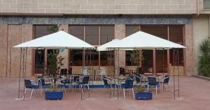 a group of tables and chairs under white umbrellas at HOTEL LAGO in Villanueva de Arosa