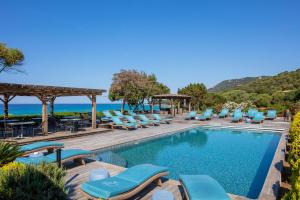 a villa with a swimming pool and lounge chairs at Hotel Le Ruesco in Olmeto