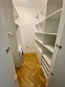 a walk in closet with white shelves and a wood floor at Chic Apartment in vibrant area - National Stadium - Saska Kępa in Warsaw
