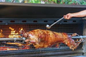 a chicken cooking on a grill with a spatula at Hotel Le Ruesco in Olmeto