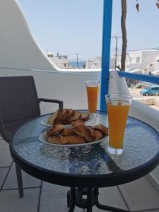 a table with a plate of food and two glasses of orange juice at Vitzileos Studios in Agios Prokopios