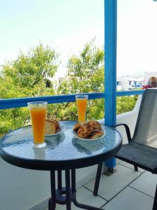 a table with a plate of food and two glasses of orange juice at Vitzileos Studios in Agios Prokopios +42 photos