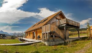 een groot houten huis met een groot terras bij La cabane du bonheur, un gite écologique 