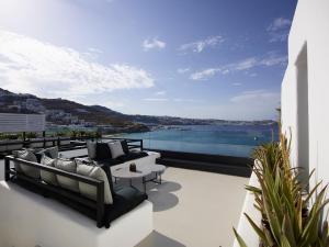 a balcony with couches and a view of the water at Nimbus Mykonos in Agios Stefanos