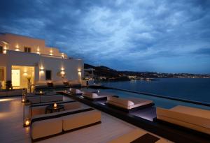 a balcony with a view of the water at night at Nimbus Mykonos in Agios Stefanos