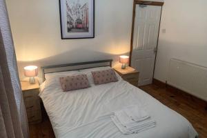 a bedroom with a white bed with two lamps at Big 6 bed house w/ 5 double beds WIFI and Netflix in Kettering