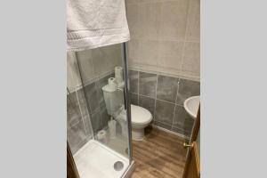 a bathroom with a toilet and a glass shower door at Big 6 bed house w/ 5 double beds WIFI and Netflix in Kettering