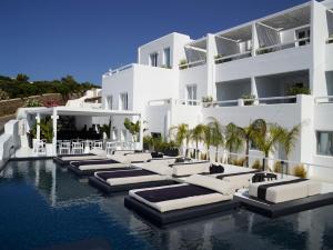 a hotel swimming pool with chaise lounges in the water at Nimbus Mykonos in Agios Stefanos
