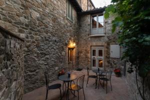 a patio with tables and chairs next to a stone building at Drogheria e Locanda Franci in Montalcino