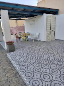 a patio with a table and chairs on a tiled floor at Letizia in Donnalucata