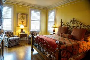 a bedroom with a bed and a chair and windows at JH Adams Inn, Trademark Collection by Wyndham in High Point