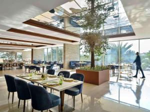 Rixos The Palm Luxury Suite Collection - Ultra All Inclusive في دبي: مطعم بطاولات وكراسي وشخص يمشي في الخلفية
