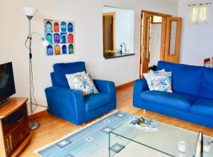 a living room with two blue couches and a glass table at Jardim do Arco "Esmee" in Arco da Calheta