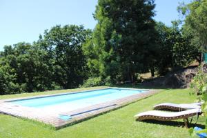 a swimming pool in the grass with two lounge chairs at Lugar da Lourida in Caminha