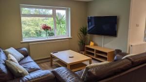 a living room with a couch and a flat screen tv at Fairwater Head in Axminster