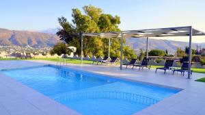 a swimming pool with chairs and umbrellas on a resort at Nina Apartment in Chania