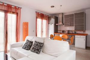a living room with a white couch and a kitchen at Real de Cartuja Apartments & Suites in Granada