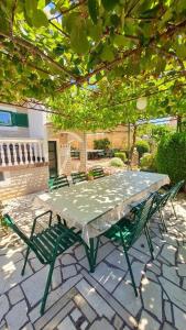 a green table and chairs on a stone patio at Apartments Crljen in Brodarica