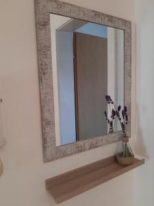 a mirror on a wall with a vase of flowers on a shelf at Sunny Lakeside Apartment in Ohrid