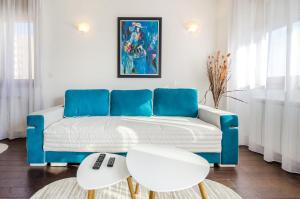 a living room with a blue couch and two white tables at A blok New Belgrade 2BD in Bežanija
