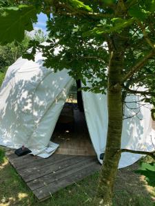 una tienda blanca sentada en una cubierta junto a un árbol en DGG Woodland Escape, en South Barrow