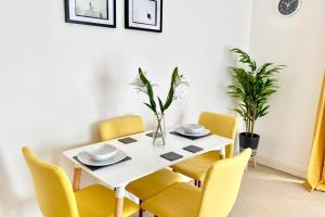 a dining room table with yellow chairs and a white table at Smartrips Apartments - Lakeside/Thurrock in West Thurrock