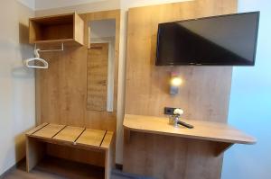 
a bathroom with a sink, mirror and a television at Pension DELAGERA in Großmehring
