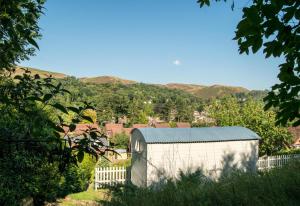 a white shed with a fence and mountains in the background at Hilltop Hut in Church Stretton