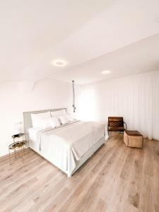 a white bedroom with a bed and a wooden floor at Penzion Jakub in Lanškroun