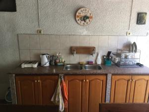 a kitchen counter with a sink and a clock on the wall at Chervenkov Guest House in Chernomorets
