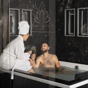 a man sitting in a bath tub with a waiter at INFINITY spa in Zrenjanin