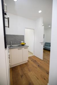 a kitchen with white cabinets and a sink and wooden floors at CASA Dersim in Bad Saulgau